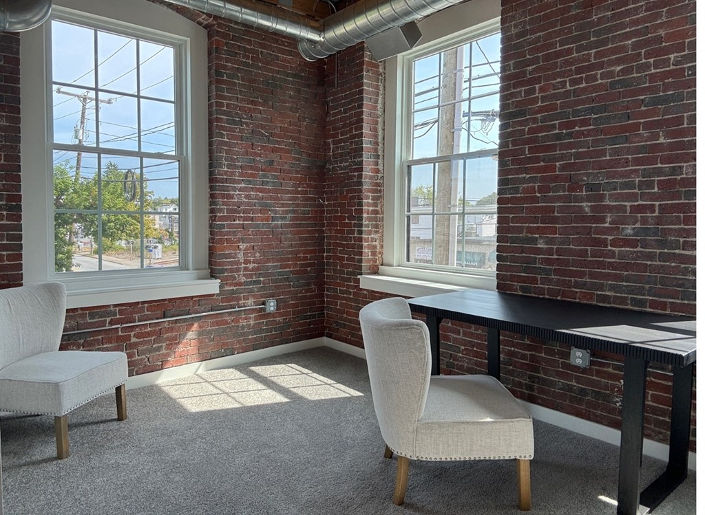 a room with two chairs and a desk and a brick wall
