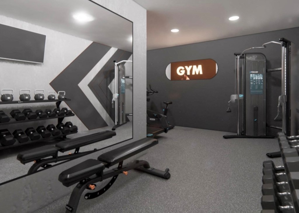 a gym with weights on the wall and a large mirror