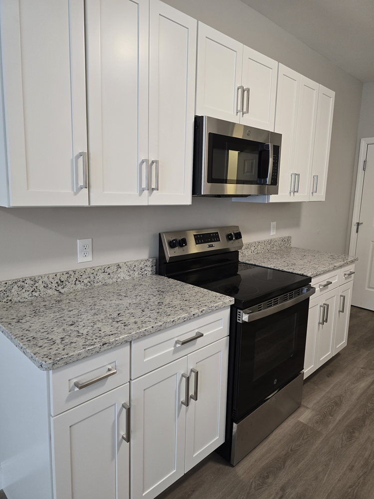 a kitchen with white cabinets and black appliances and granite counter tops