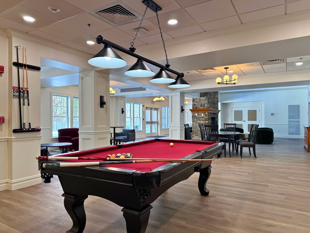 A pool table is in the middle of a room with a red cloth.