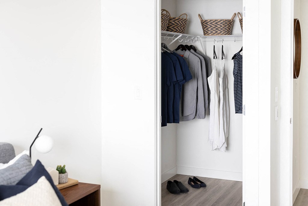 a closet filled with clothes and shoes in a living room
