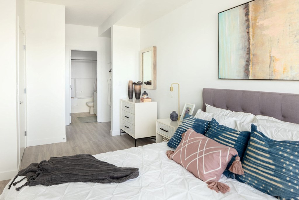 a bedroom with a bed and pillows and a bathroom with a sink