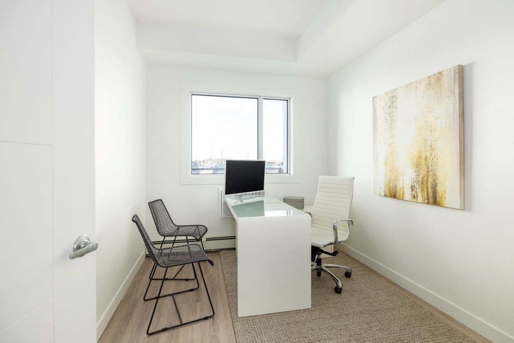 an office with a desk and two chairs and a window