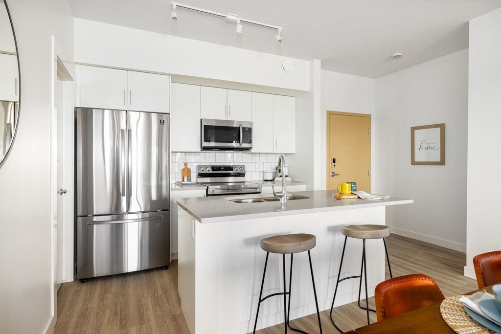a kitchen with stainless steel appliances and a bar with three stools