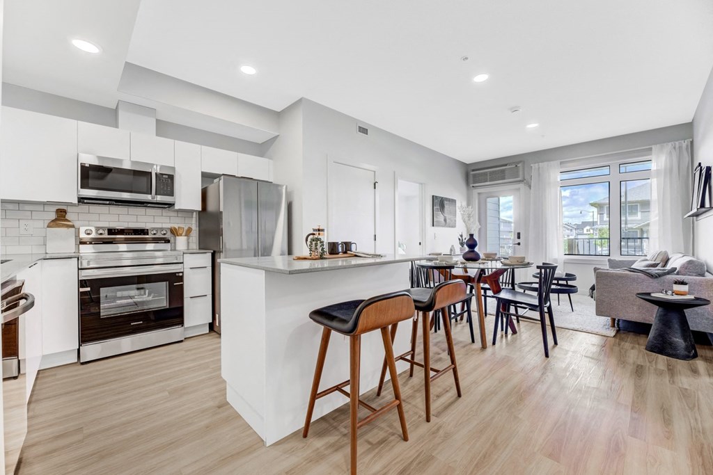 a living area with a kitchen and a dining area with bar stools