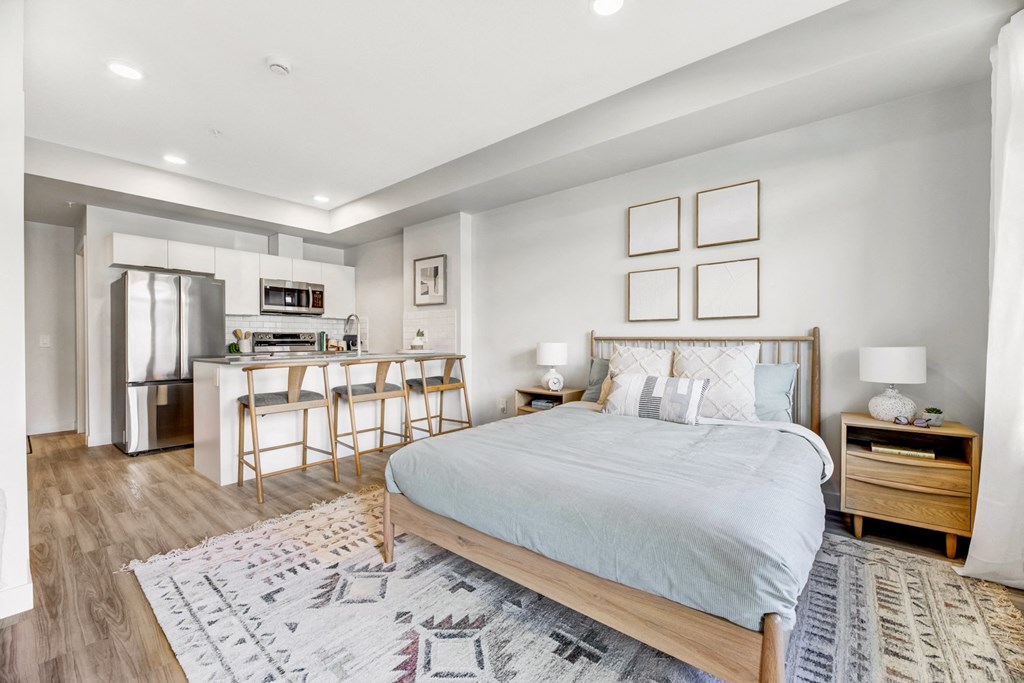 a bedroom with a bed and a kitchen with a breakfast bar