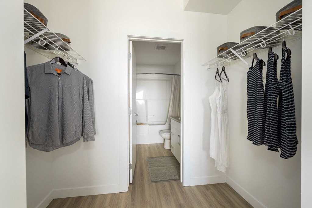 a closet with a door to a bathroom and some clothes