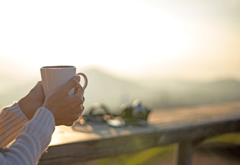a person holding a cup of coffee on a balcony