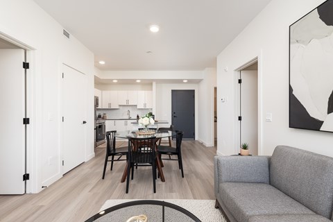 A modern living room with a dining table and grey couch.