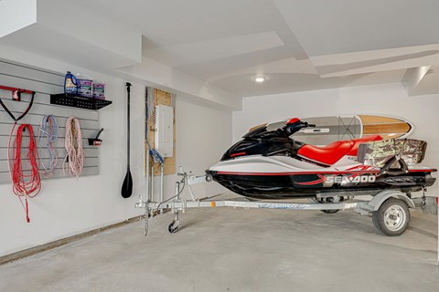 A red and black Sea-Doo jet ski is on a trailer in a garage.