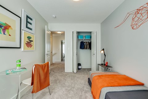 A bedroom with a bed, a chair, and a painting on the wall.
