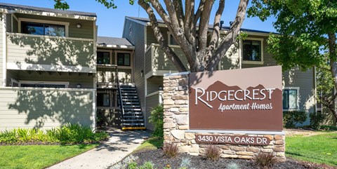 A sign for Ridgecrest Apartment Homes stands in front of a building.