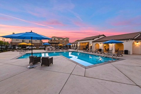 A swimming pool surrounded by lounge chairs and umbrellas.