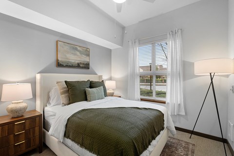 A bedroom with a bed, nightstand, and a painting on the wall.