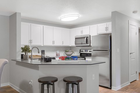 A kitchen with white cabinets and a grey counter.