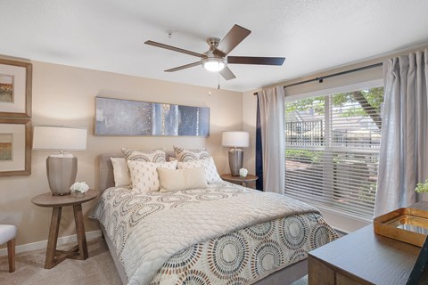A bedroom with a large bed and a ceiling fan.