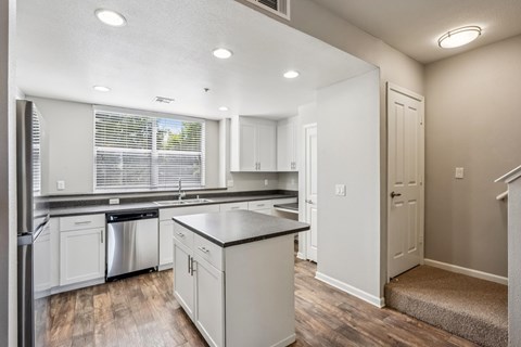 A kitchen with white cabinets and a black countertop.