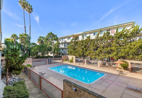 A pool surrounded by a fence and trees.