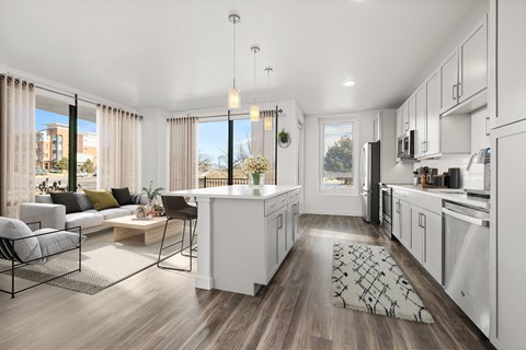 A modern kitchen with white cabinets and a wooden floor.
