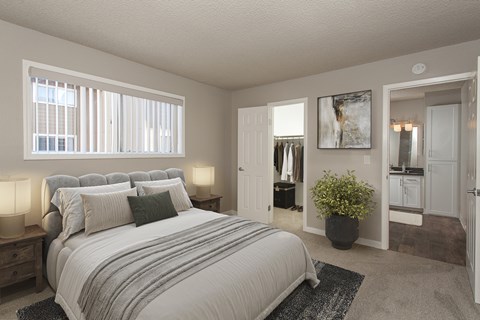 A bedroom with a large bed and a potted plant.