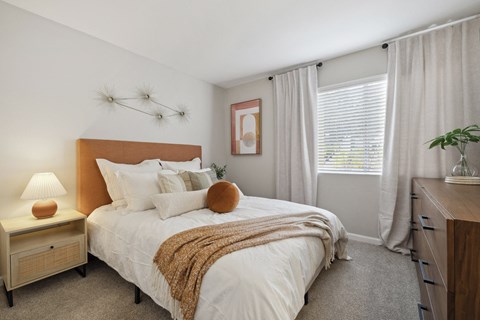 A bedroom with a bed, nightstand, and window.