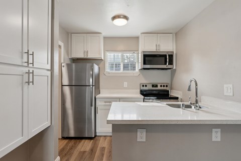 A kitchen with white cabinets and a stainless steel refrigerator.