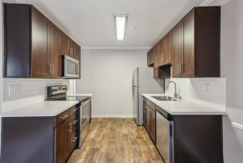 A kitchen with dark wood cabinets and stainless steel appliances.