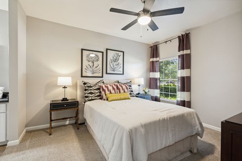 A bedroom with a bed, nightstand, and two wall art pieces.