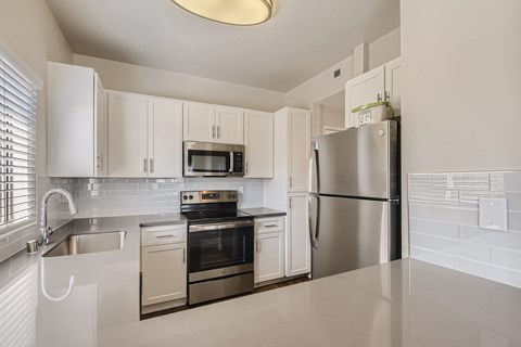 A kitchen with white cabinets and appliances.
