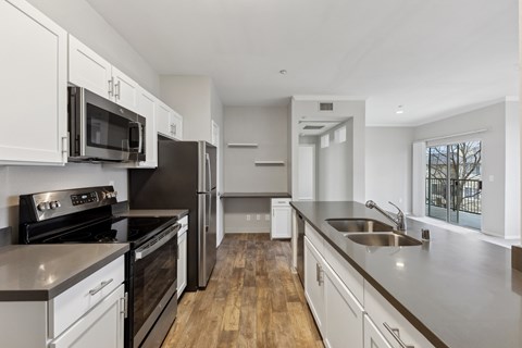 A modern kitchen with white cabinets and stainless steel appliances.