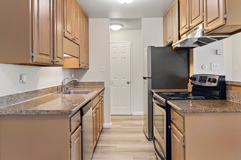 A kitchen with brown cabinets and a black refrigerator.
