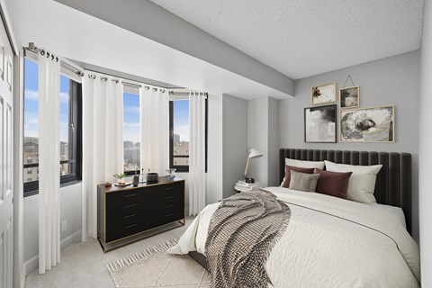 A bedroom with a large bed and a window with curtains.