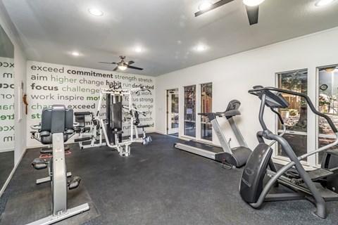 A gym room with a row of treadmills and a wall of motivational words.