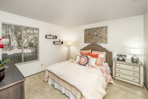 A bedroom with a bed, nightstand, and lamp.