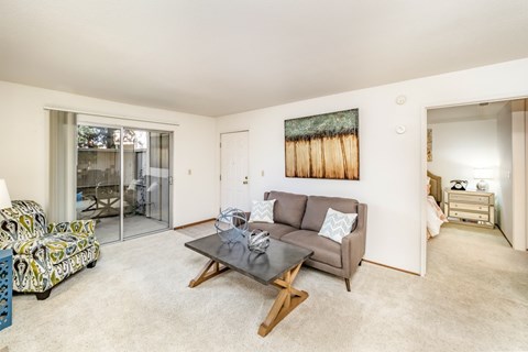 A living room with a couch, coffee table, and a painting on the wall.