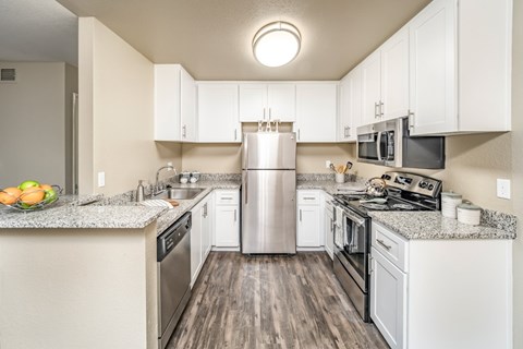 A kitchen with white cabinets and a granite countertop.