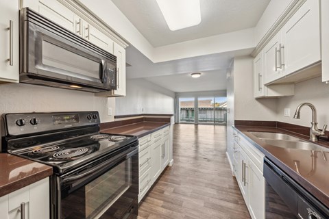 A kitchen with white cabinets and a black stove top oven.