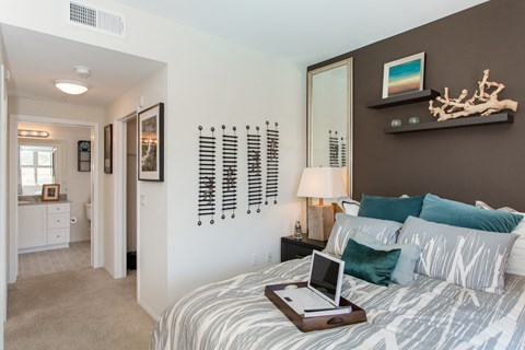 A bedroom with a bed, nightstand, and a laptop on the bed.
