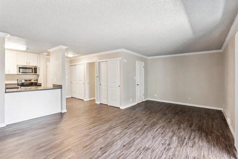 A spacious room with wooden flooring and white walls.