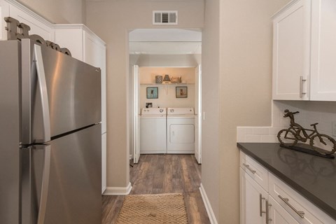 A kitchen with a stainless steel refrigerator and white cabinets.