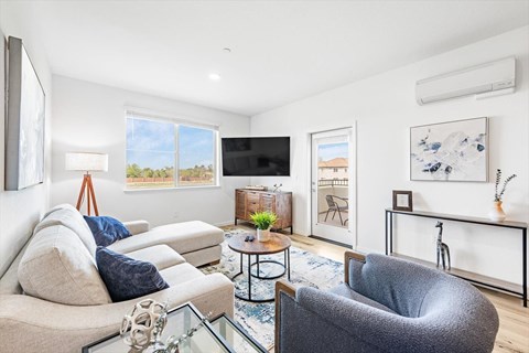 A living room with a white couch, a grey armchair, and a glass coffee table.