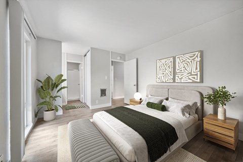 A bedroom with a large bed and a plant on the nightstand.