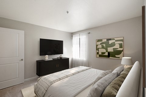 A bedroom with a bed, a television, and a painting on the wall.