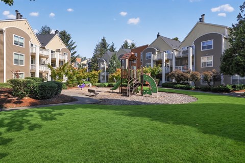 A playground in a grassy area surrounded by apartment buildings.