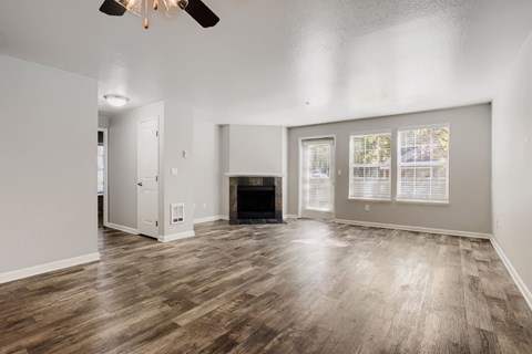 A spacious living room with a fireplace and wood flooring.