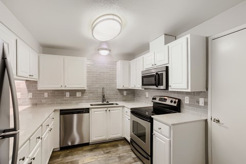 A kitchen with white cabinets and appliances.