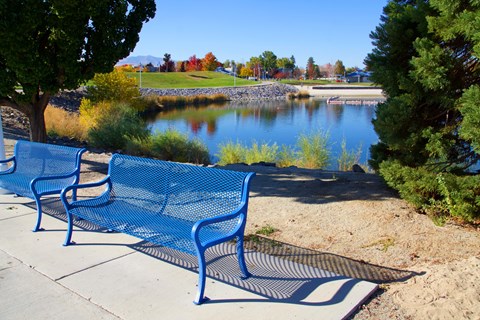 two blue benches overlooking a lake at a park