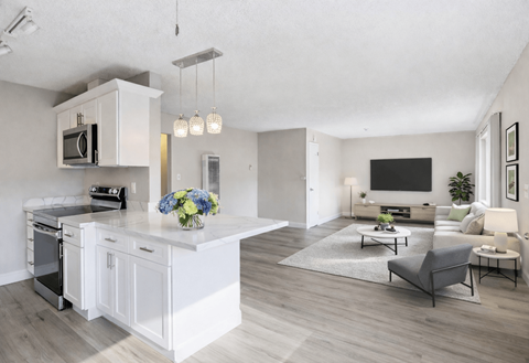 A modern kitchen with a large island and a living room with a couch and a coffee table.