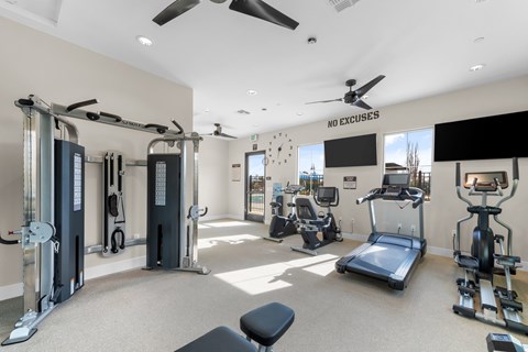 A gym with a variety of equipment including treadmills, weights, and a bench.