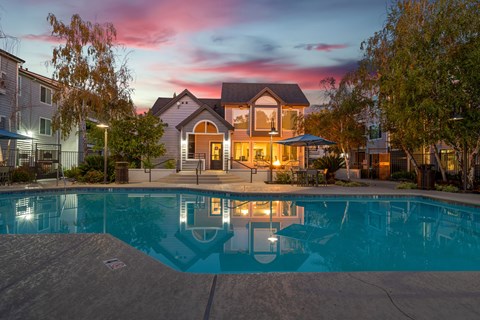 a swimming pool at dusk with a house in the background
